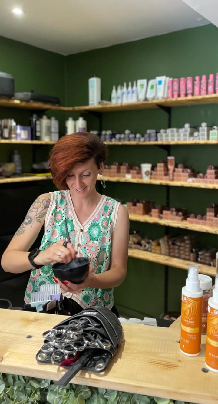 La P’tite Brune, fondatrice du salon, préparant une coloration devant les étagères de produits