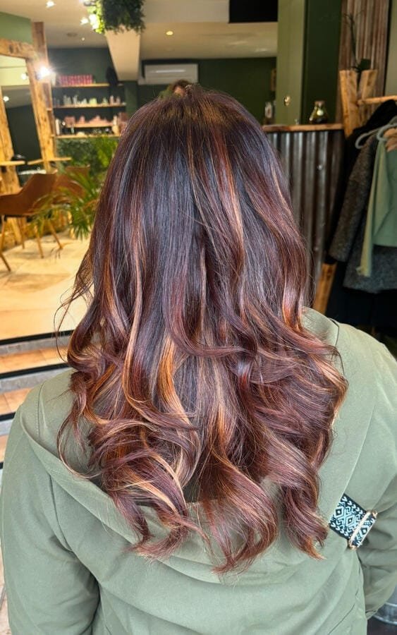 Coloration cuivrée aux reflets miel, boucles souples sur cheveux longs