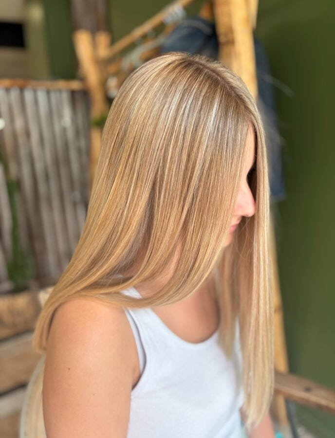 Cheveux longs raides et lisses éclaircis de fines mèches blondes, vus de profil