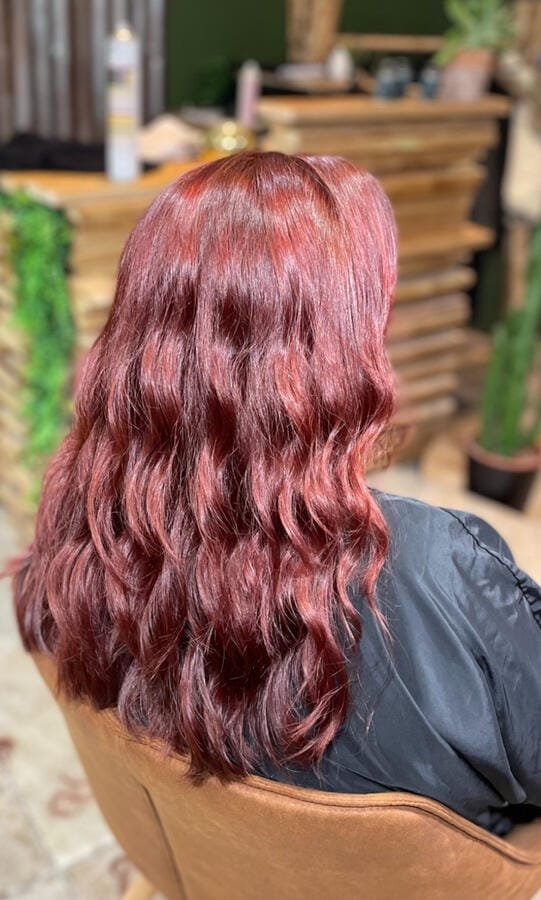 Coloration rouge profond sur cheveux longs ondulés